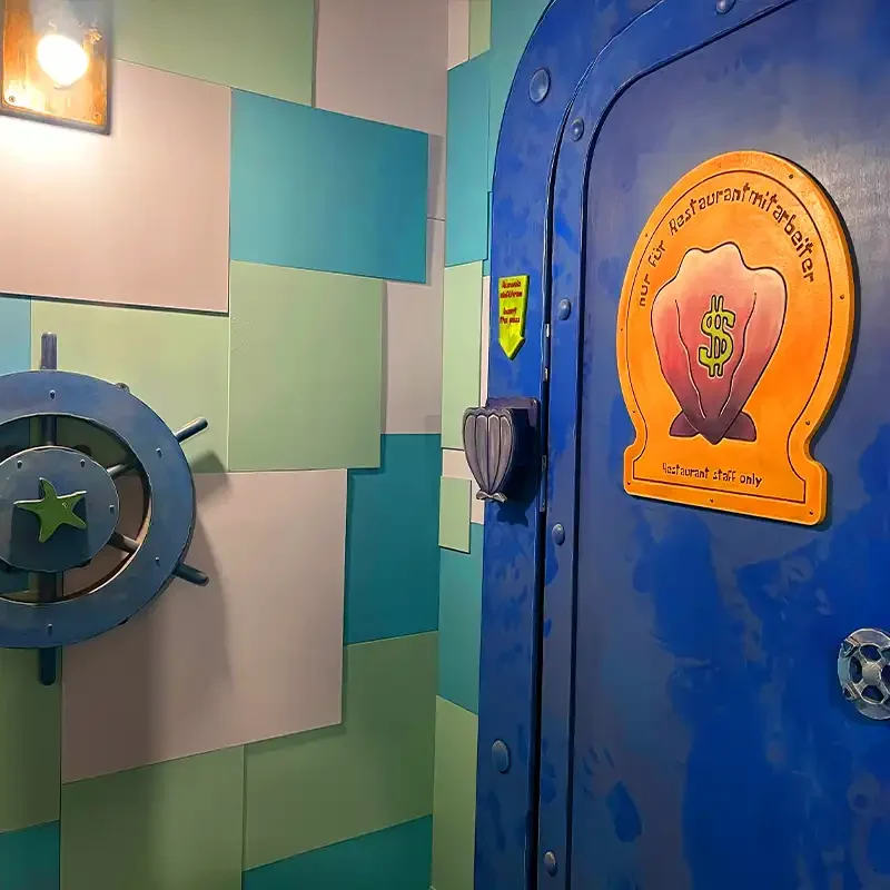 Thematisch gestaltete blaue Tür im Escape Room Krabbenburger in Zürich mit Restaurant-Schild und maritimer Dekoration.