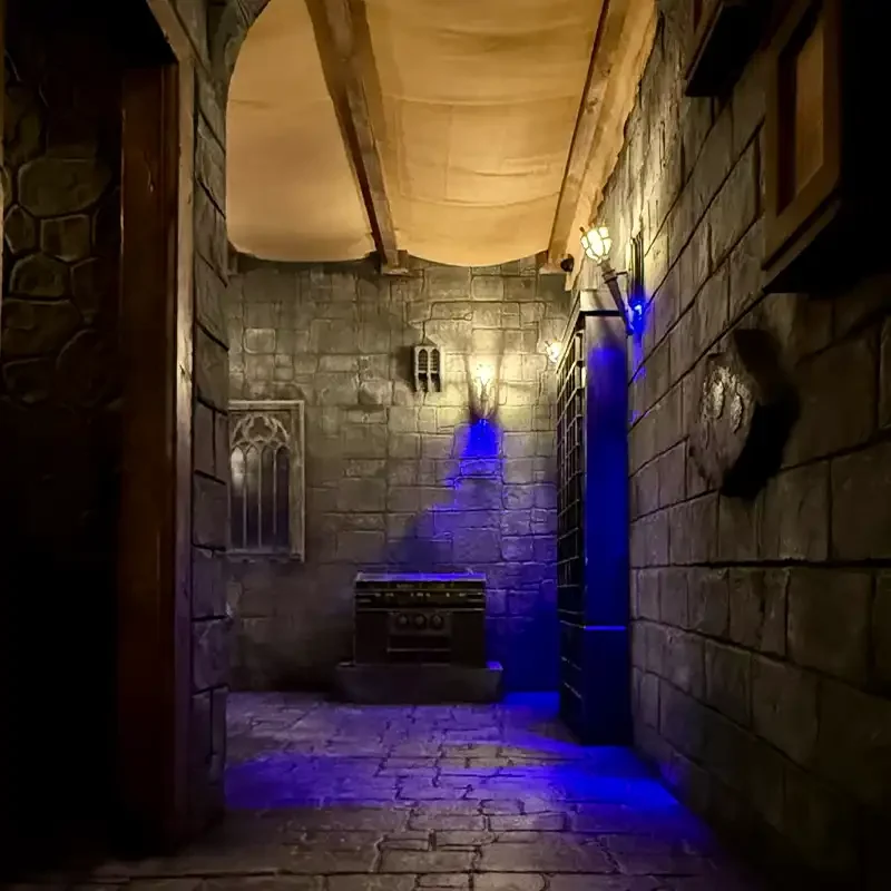 Mystischer Gang im Escape Room H. Potter bei Final Escape Zürich mit Steinwänden, Fackeln und blauer Effektbeleuchtung.